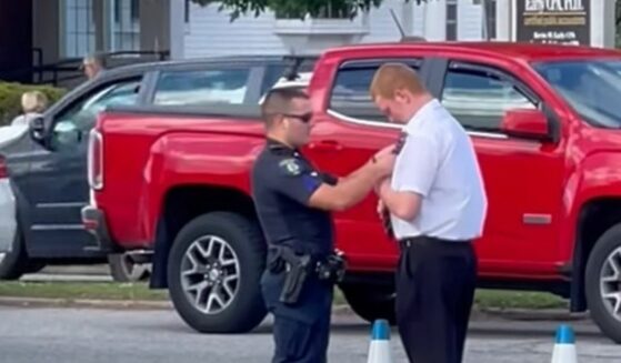 Police officer helps young graduate with tie before graduation ceremony.
