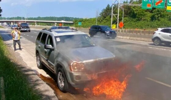 Burning car on the side of the road.