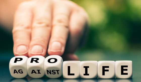 Hand turns dice and changes the expression "against life" to "pro life"