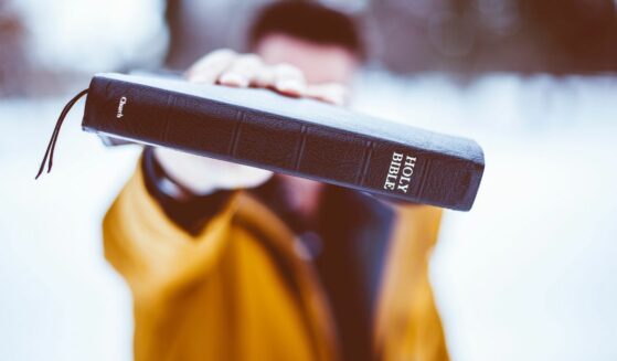 Man holding a bible in winter outdoors.