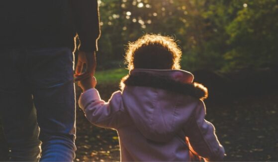 Young kid held by a parent outdoors.