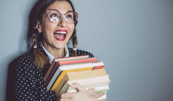 College bookworm girl holding stack of books.