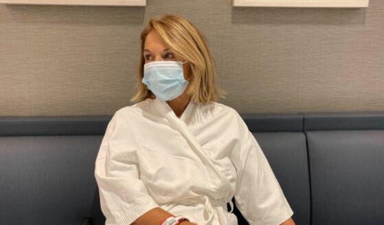 Katie Couric in a mask and robe at the hospital