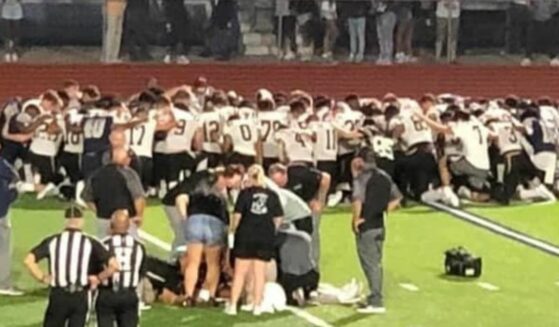 Two teams of Texas football players kneeling in prayer, interceding for an injured player.