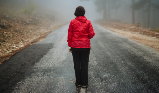 Photograph of woman in red coat walking alone in road from the Walking by Faith article on Liftable.com