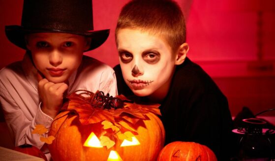 Two kids in costume with a jack o'lantern